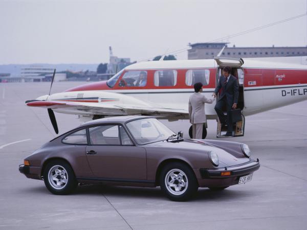 1977 Porsche 911 Carrera parked in front of a plane